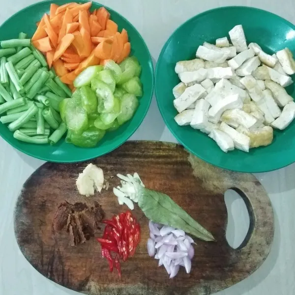 Siapkan semua bahan, cuci bersih. Iris serong wortel, belimbing wuluh, dan cabai merah keriting. Potong buncis dan tahu sepanjang korek api. Iris halus bawang merah dan bawang putih. Geprek lengkuas.