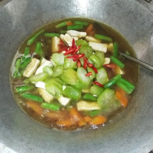 Masukan tahu, belimbing wuluh, dan cabai merah. Aduk hingga tercampur rata.