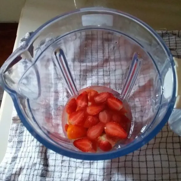 Siapkan gelas blender. Masukkan air es, gula pasir, potongan buah tomat dan strawberry.