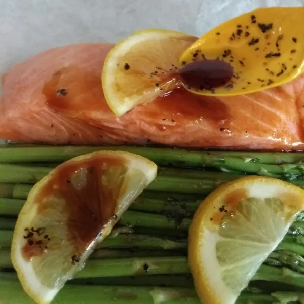 Siram salmon dan asparagus dengan bumbu.