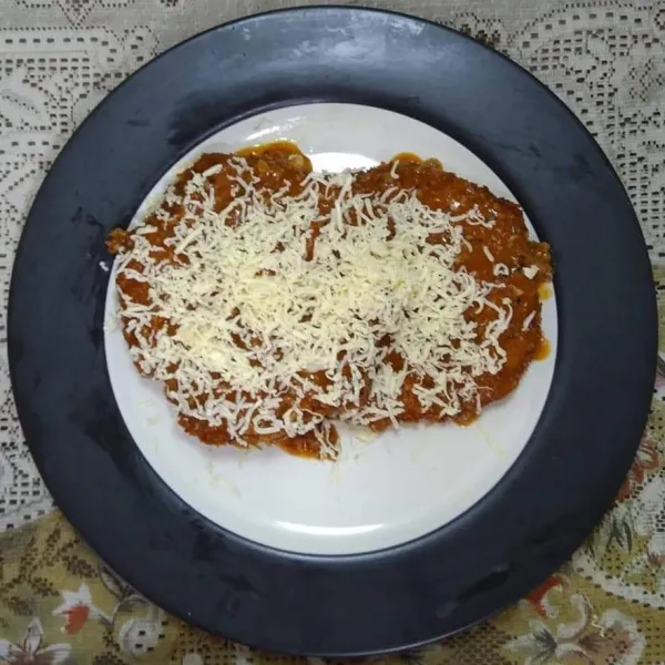 Angkat, tiriskan dan letakkan di dalam piring anti panas, tambahkan saus bolognese dan keju mozzarella.