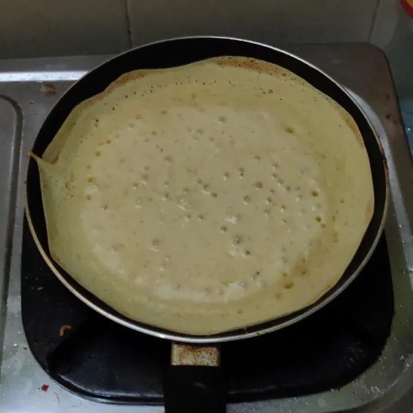 Panaskan teflon dengan api kecil. Tuang adonan dan basahi pinggir teflon.