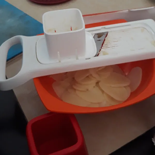 Jika kentang sudah keras, keluarkan dari kulkas dan mulai diiris tipis