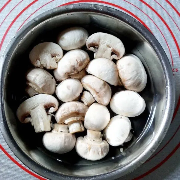 Kupas kulit paling luar, belah dua jika jamur terlalu besar. Cuci dan tiriskan.