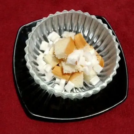 Roti tawar dipotong dadu. Kelapa juga dipotong dadu kecil-kecil. Tata dalam mangkok.