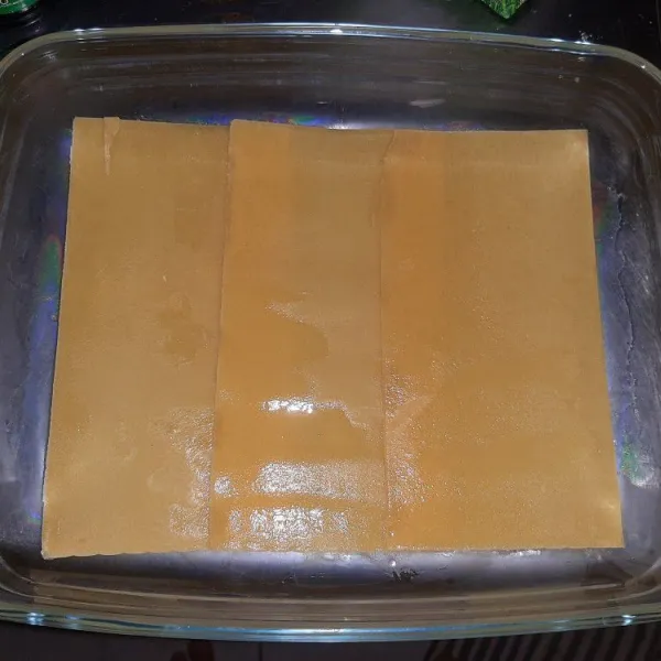 Olesi loyang dengan margarin, kemudian letakkan kulit lasagna.
