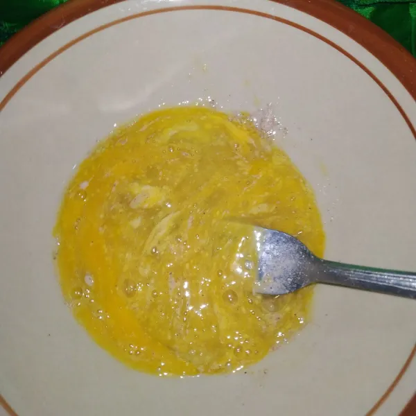 Di wadah lain, pecahkan 1 butir telur kocok bersamaan dengan garam, merica bubuk dan kaldu bubuk.