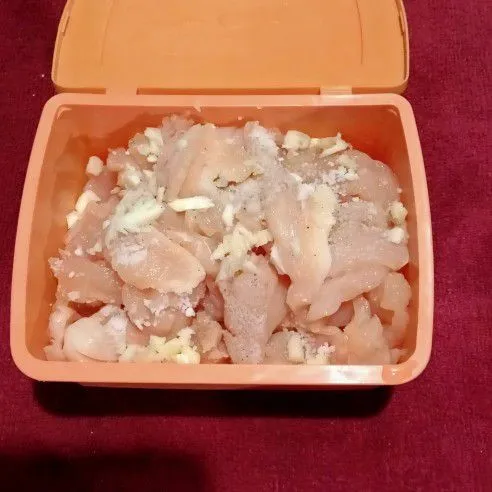 Siapkan daging ayam dalam wadah. Tambahkan garam, penyedap rasa dan bawang putih cincang ke dalam ayam. Ratakan lalu diamkan 15 menit.