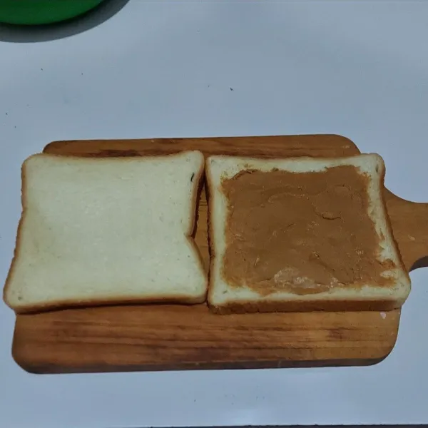 Oleskan selai pada satu sisi roti tawar lalu tutup kembali dengan roti tawar.