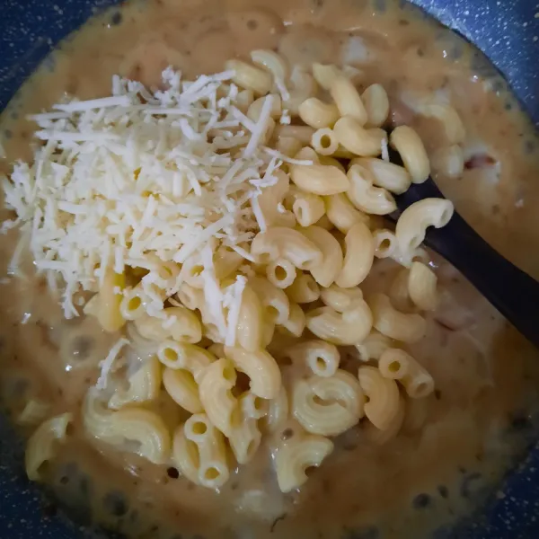 Masukkan makaroni dan keju parut, aduk rata, dan koreksi rasa.