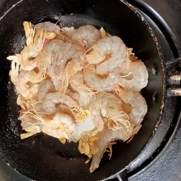 Panaskan minyak goreng lalu tumis bawang putih yang telah diiris tipis kemudian masukkan udang.