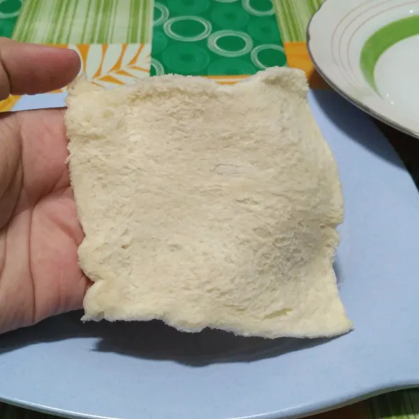 Gilas roti tawar menggunakan rolling pin agar pipih.