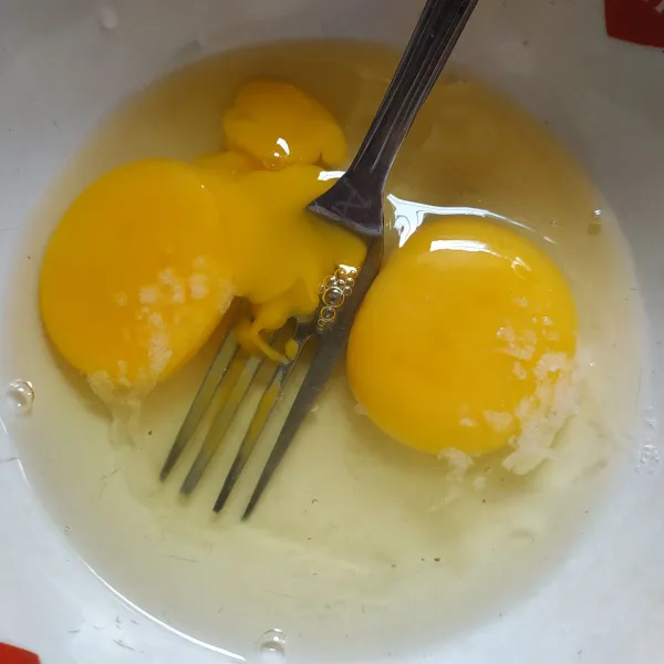 Pecahkan telur ke dalam mangkuk, tambahkan garam lalu kocok lepas.