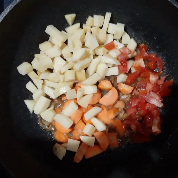 masukkan kentang, wortel, tomat, bawang putih dan kecap inggris. aduk rata.