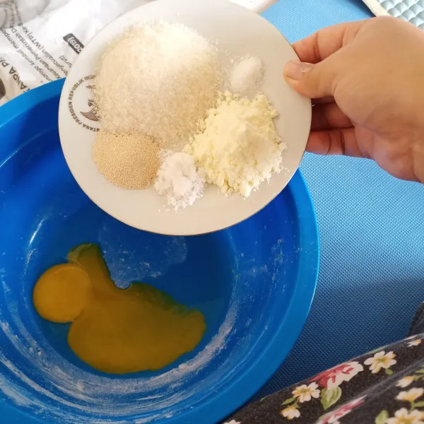 Campurkan kuning telur, gula pasir, garam, ragi instan, vanili dan susu bubuk. Kemudian kocok hingga gula halus.