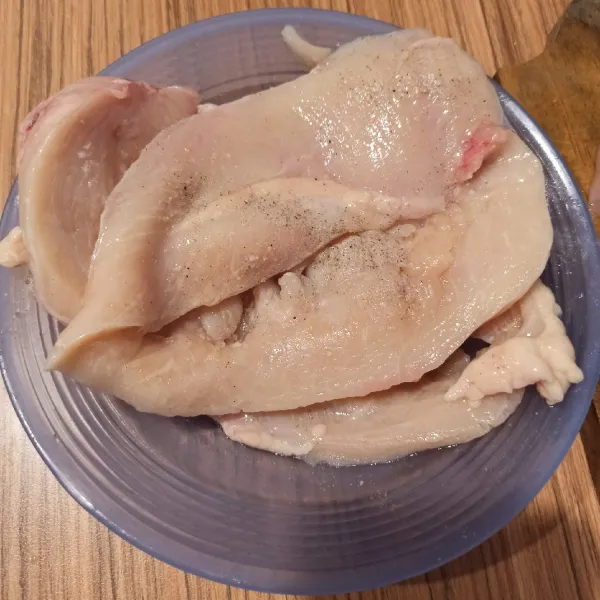 Belah 2 dada ayam, kemudian pipihkan, tumbuk dengan tumbukan daging. Taburi dengan garam dan merica bubuk.