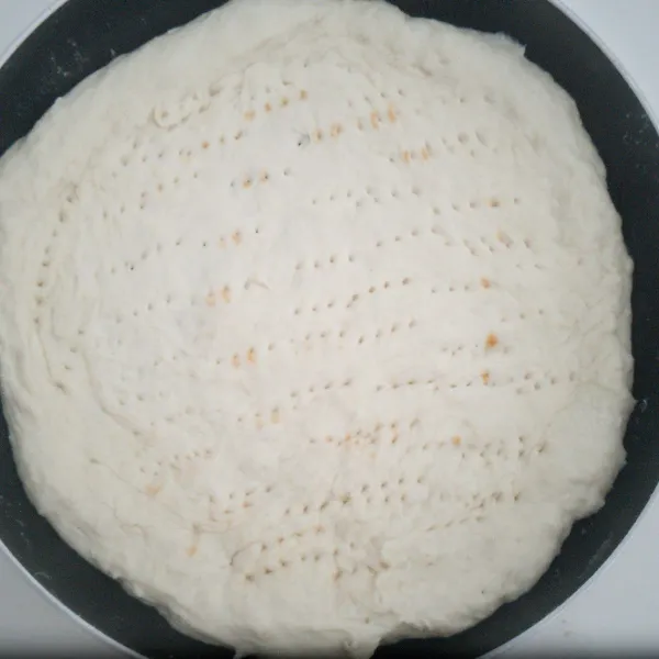 Kempeskan adonan, bagi menjadi 3 bagian. Lumuri tangan dengan terigu lalu lebarkan adonan langsung di teflon dengan cara dipijit  dan didorong dengan jari. Tusuk tusuk permukaan adonan dengan garpu