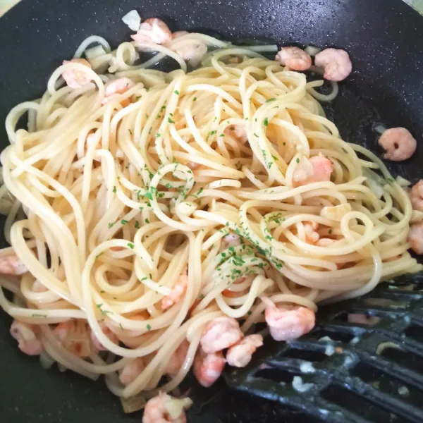 Kecilkan api, taburi spaghetti dengan parsley dan bubuk cabe. Aduk hingga rata, lalu matikan api. Ruang spaghetti ke atas piring saji.