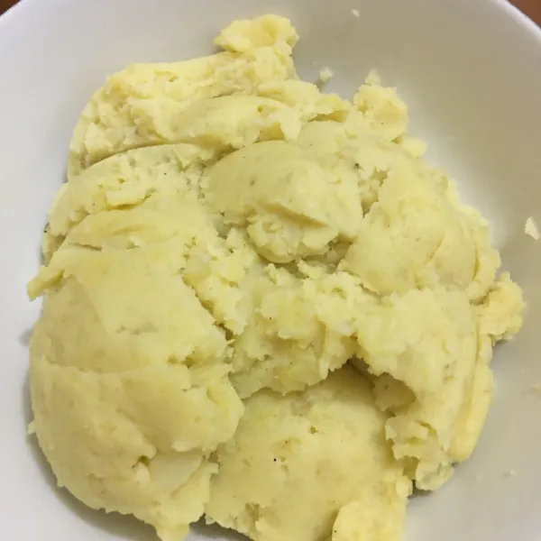 Hancurkan kentang hingga halus dan tambahkan mentega. Aduk hingga tercampur rata. Lalu, campurkan susu bubuk, garam, gula, lada, dan kaldu jamur. Aduk hingga merata semua.
