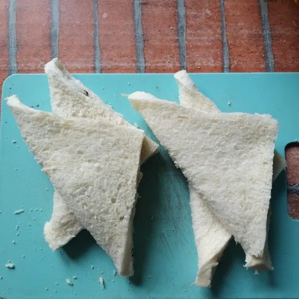 Olesi roti tawar dengan pasta coklat kemudian lipat bentuk segitiga. Rekatkan ujung roti dengan menekannya menggunakan garpu.