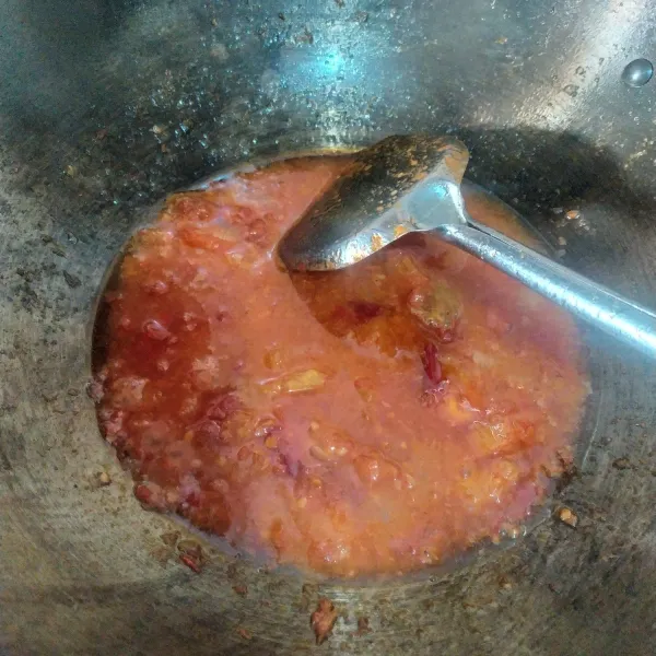 Panaskan 4 sdm minyak. Goreng bumbu sambal sebentar. Ulek sampai halus lalu masukkan kembali ke wajan. Masak sampai harum. Masukkan irisan tomat, beri setengah gelas air.