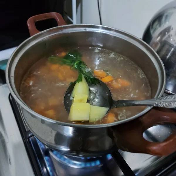 Masukkan wortel dan kentang. Masak sampai hampir matang. Masukkan garam, gula dan kaldu bubuk jamur, aduk rata lagi.