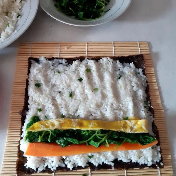 letak 1lembar nori diatas gimbab roll.Beri rata nasi goreng diatasnya,kemudian beri secukupnya bayam,wortel dan telur.
