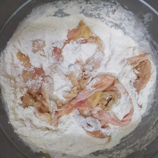 Masukkan kulit ayam ke adonan tepung kering, sedikit demi sedikit. Lapisi kulit ayam dengan tepung. Jangan dilakukan sekaligus karena tepung akan jadi basah dan menggumpal.