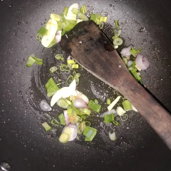 Rajang bawang merah dan bawang putih ditumis dengan sedikit minyak. Lalu tambahkan daun bawan. Tumis hingga harum.