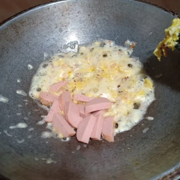 Tumis bawang sampai harum, masukkan telur lalu orak arik, tambahkan potongan sosis