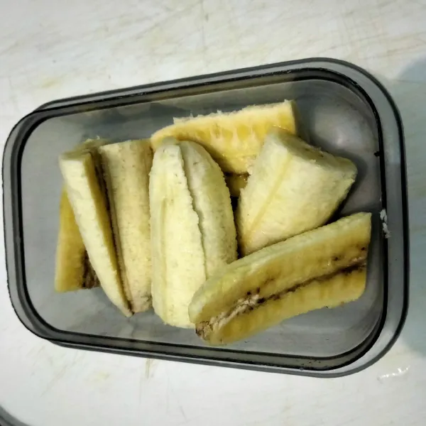 Belah pisang menjadi 2 bagian. Lalu potong lagi menjadi 2 bagian atau sesuaikan dengan ukuran rotinya.