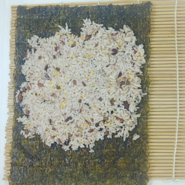 Ratakan nasi diatas rumput laut, sisakan sedikit nasi untuk perekat.