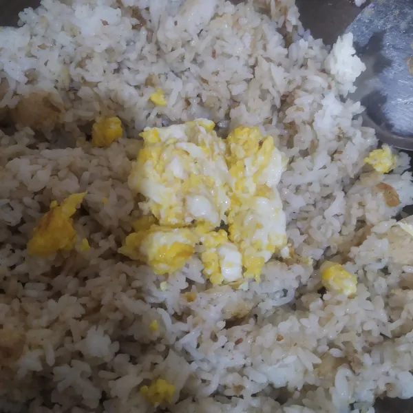 Masukkan nasi, aduk rata beri garam dan kaldu bubuk, masukkan telur orak-arik, aduk