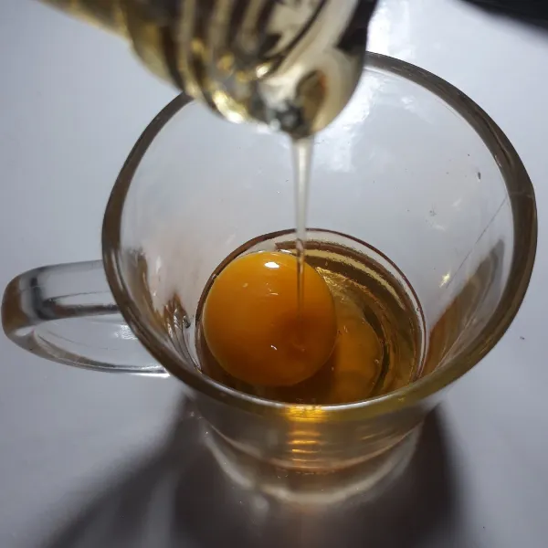 Masukkan kuning telur dan madu ke dalam gelas.