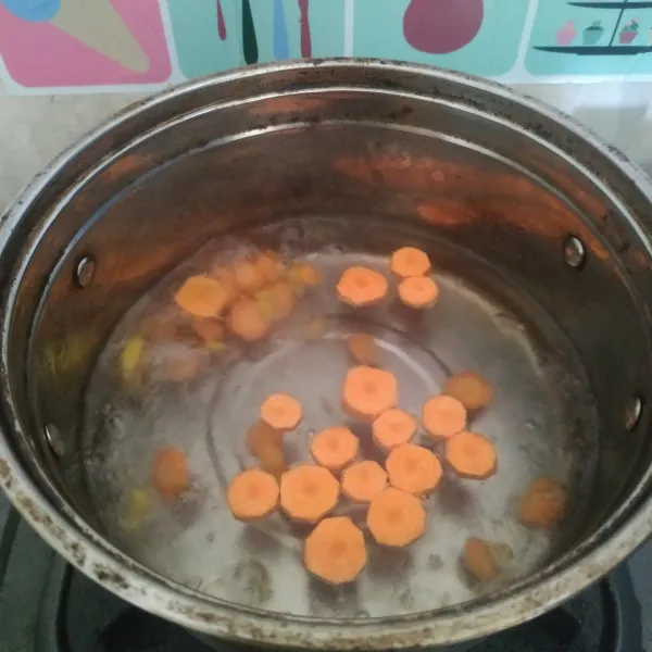 Didihkan air di panci, masukkan wortel dan jahe. Masak sampai wortel setengah matang.