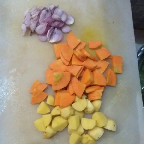 Potong-potong kentang dan wortel. Iris juga bawang merah.