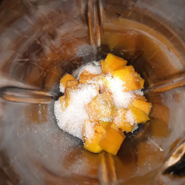 Masukkan mangga yang sudah beku ke dalam blender, beri gula pasir