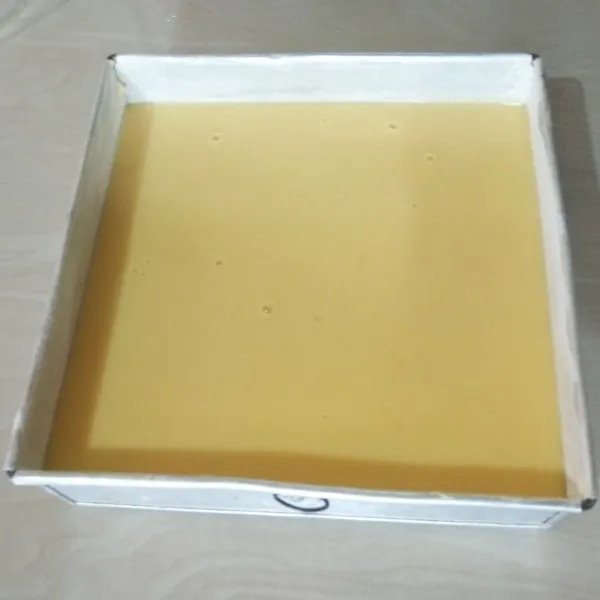 Oles loyang dengan margarin lalu taburi dengan terigu. Masukan adonan puding tape ke dalam loyang ukuran 20x20 cm.