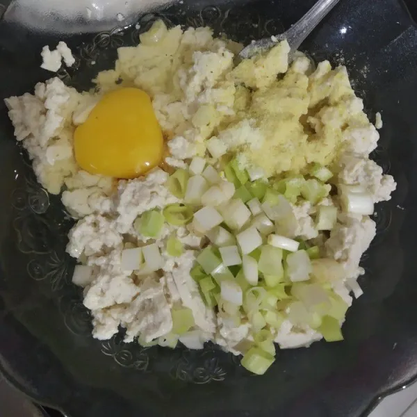 Hancurkan tahu mengunakan garpu. Tambahkan telur, daun bawang, kaldu bubuk, merica bubuk dan bawang putih bubuk. Aduk rata.