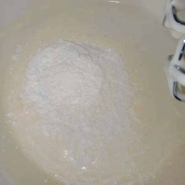 Saat sudah putih berjejak, tambahkan tepung, soda kue garam, dan vanili. Aduk rata dan mixer sebentar