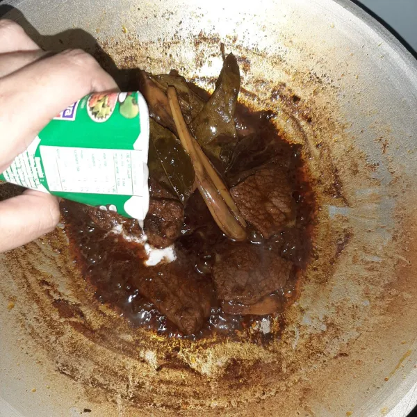Setelah menyusut, masukkan santan kelapa. Kecilkan api.