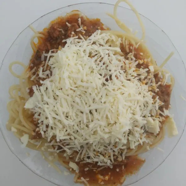 Siapkan spaghetti ke dalam wadah, tambahkan saus bolognaise dan parutan keju