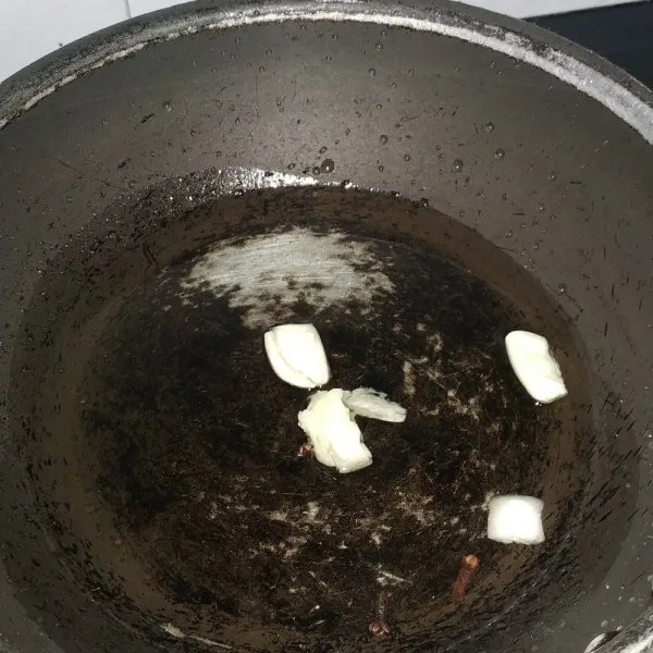 Campurkan minyak, bawang putih geprek, dan cengkeh. Masak minyak hingga meletup-letup