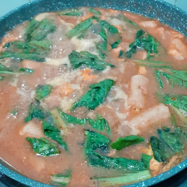 Tambahkan air dan aduk rata. Masak hingga mendidih. Tambahkan gula, garam, dan sawi. Koreksi rasa. Masak hingga sawi layu. Sajikan.