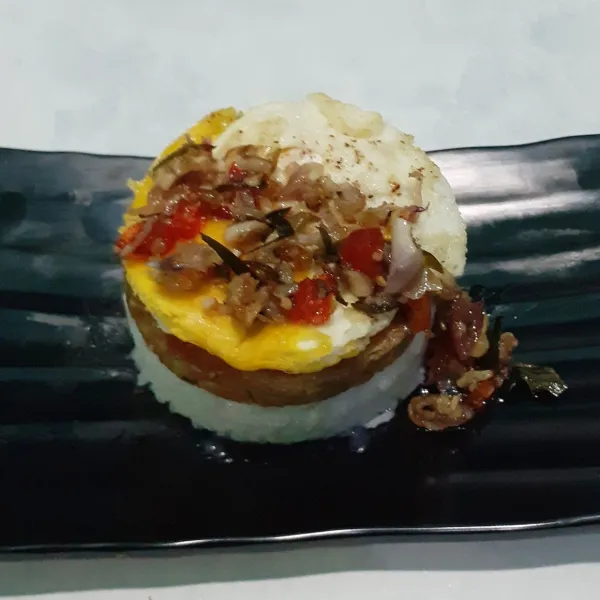 Letakkan patty tempe, telur ceplok, dan sambal matah di atasnya. Tutup dengan nasi lagi. Burger nasi tempe patty siap disajikan.
