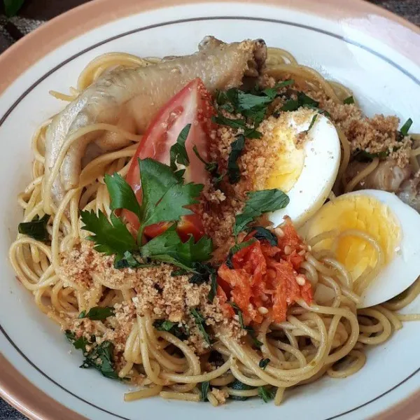 Tuang spaghetti ke piring saji. Tambahkan telur rebus, irisan tomat dan sambal cabe rawit merah. Taburi atasnya dengan koya dan irisan daun seledri. Sajikan selagi masih hangat.