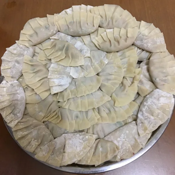 Siapkan kulit gyoza berbentuk bulat, taruh ditengahnya satu sendok teh isian yang telah disiapkan. Basahi pinggiran kulit dengan air, kemudian lipat menjadi dua, dan lipat-lipat pinggir kulit.