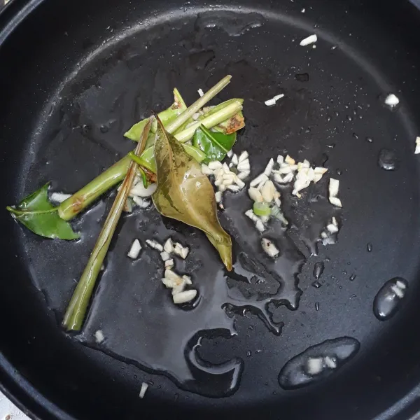 Panaskan minyak goreng. Lalu tumis bawang putih, daun bawang, daun jeruk, daun salam, lengkuas dan serai hingga keluar aroma bumbunya.