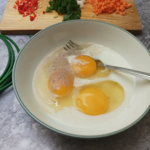 Dalam mangkuk, masukkan telur, susu, garam, kaldu bubuk dan merica bubuk. Kocok rata dengan garpu.