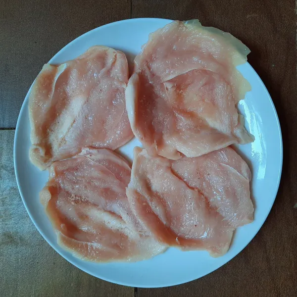 Membuat Chicken Schnitzel: belah dua dada ayam tapi tidak putus. Lumuri seluruh permukaannya dengan garam dan merica bubuk.